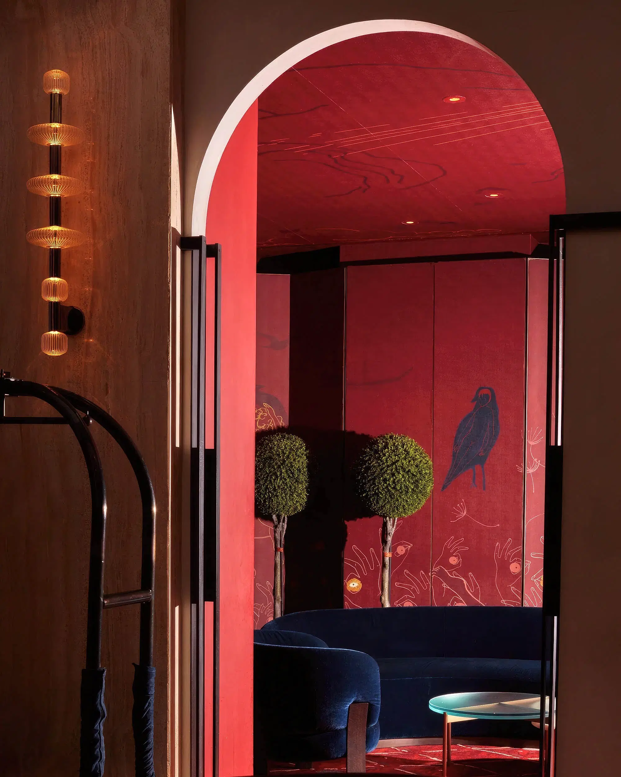 A lounge area with red walls and ceiling and blue velvet couch.