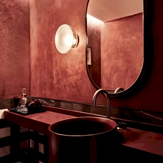 A moody red sink area of the bathroom of the Conservatory Suite at Park Lane New York.
