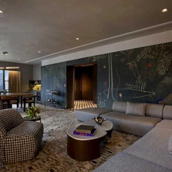 A large living area with sectional couch, dining area and walls with hand painted murals at Park Lane New York.