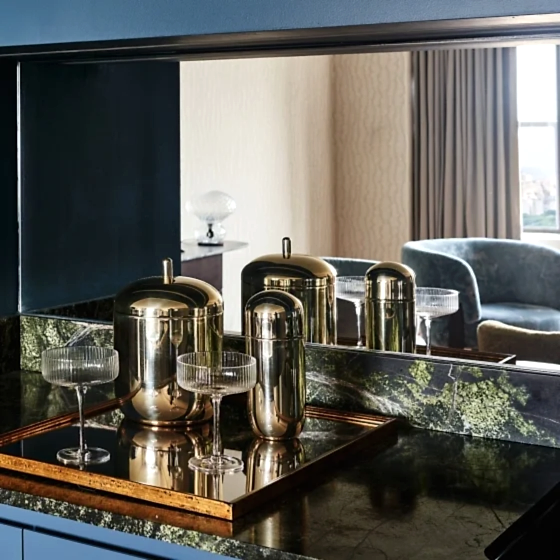 An elegant bar with delicate glasses and gold tumblers in a suite at Park Lane New York.