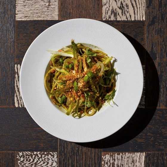 A green pasta dish with toasted breadcrumbs on top.