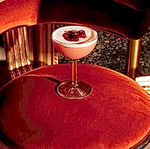 A pink cocktail on a red velvet cushion.