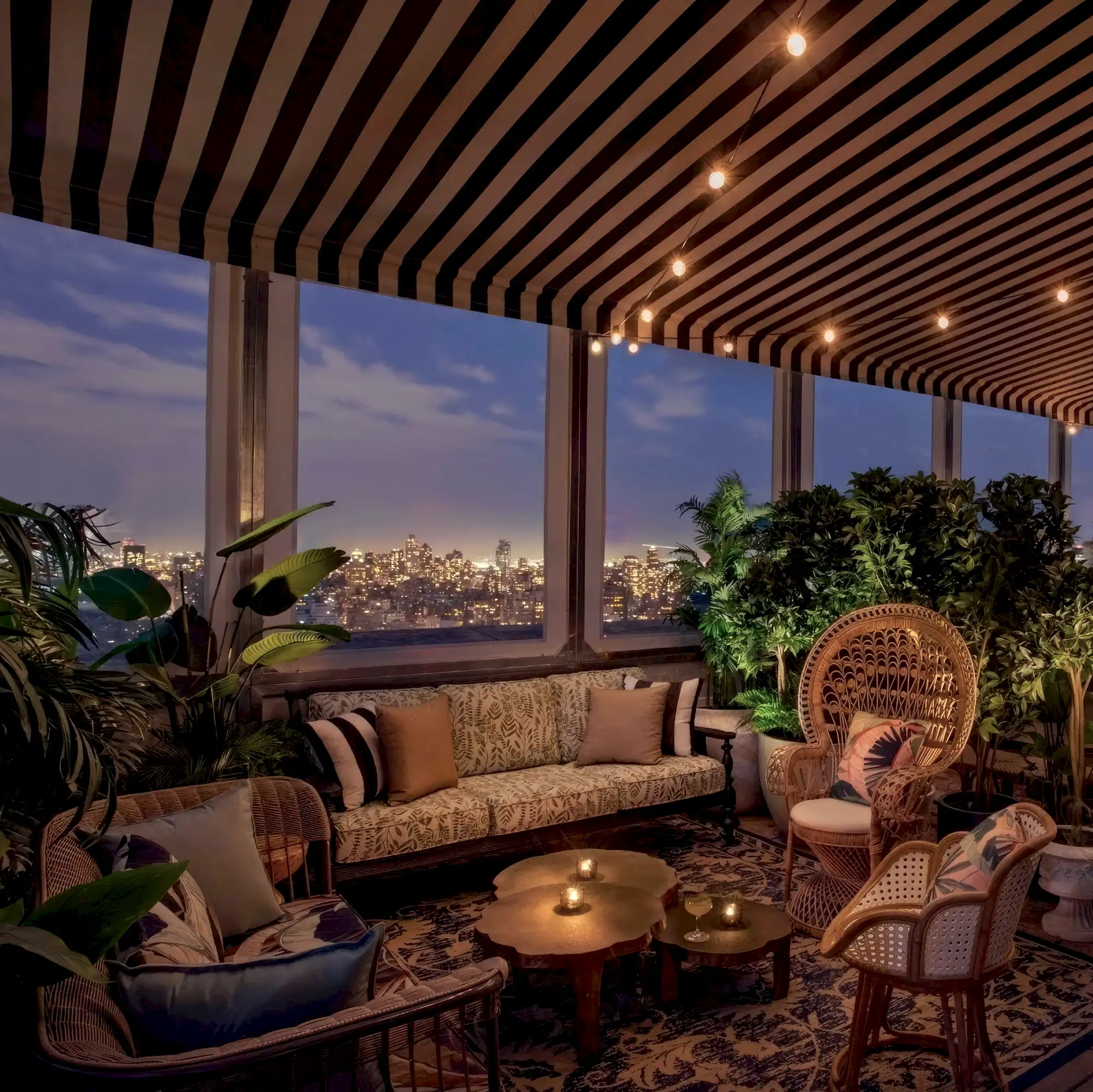 A cozy lounge area with warm lighting at dusk, New York City skyline in the background.