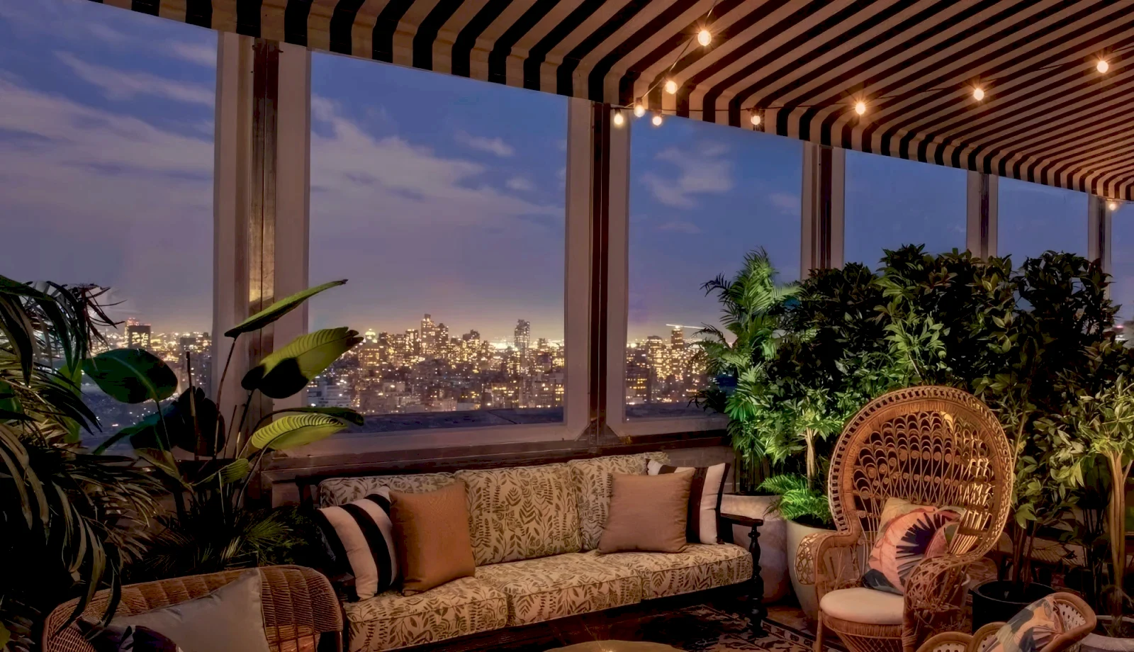 A cozy lounge area with warm lighting at dusk, New York City skyline in the background.