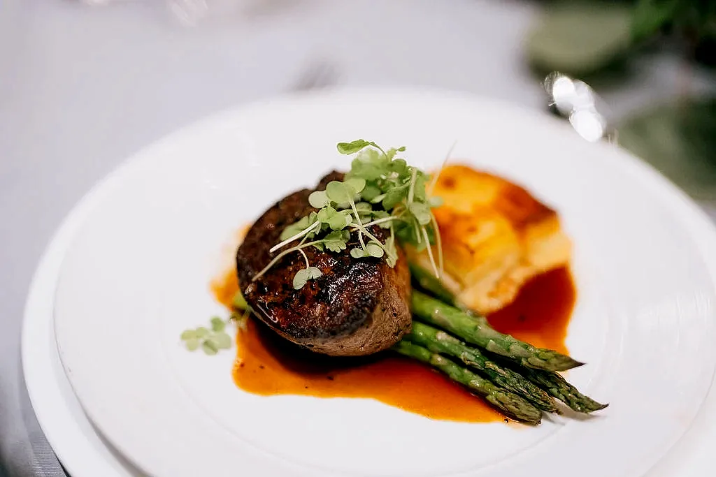 plated dish featuring a cut of filet mignon served with asparagus and potatoes.