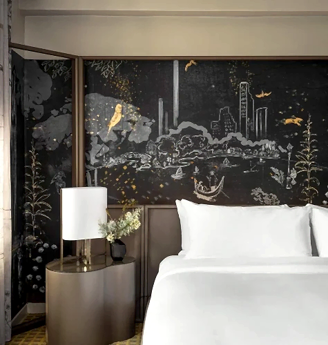 A king bed with painted mural behind it in a suite at Park Lane New York.
