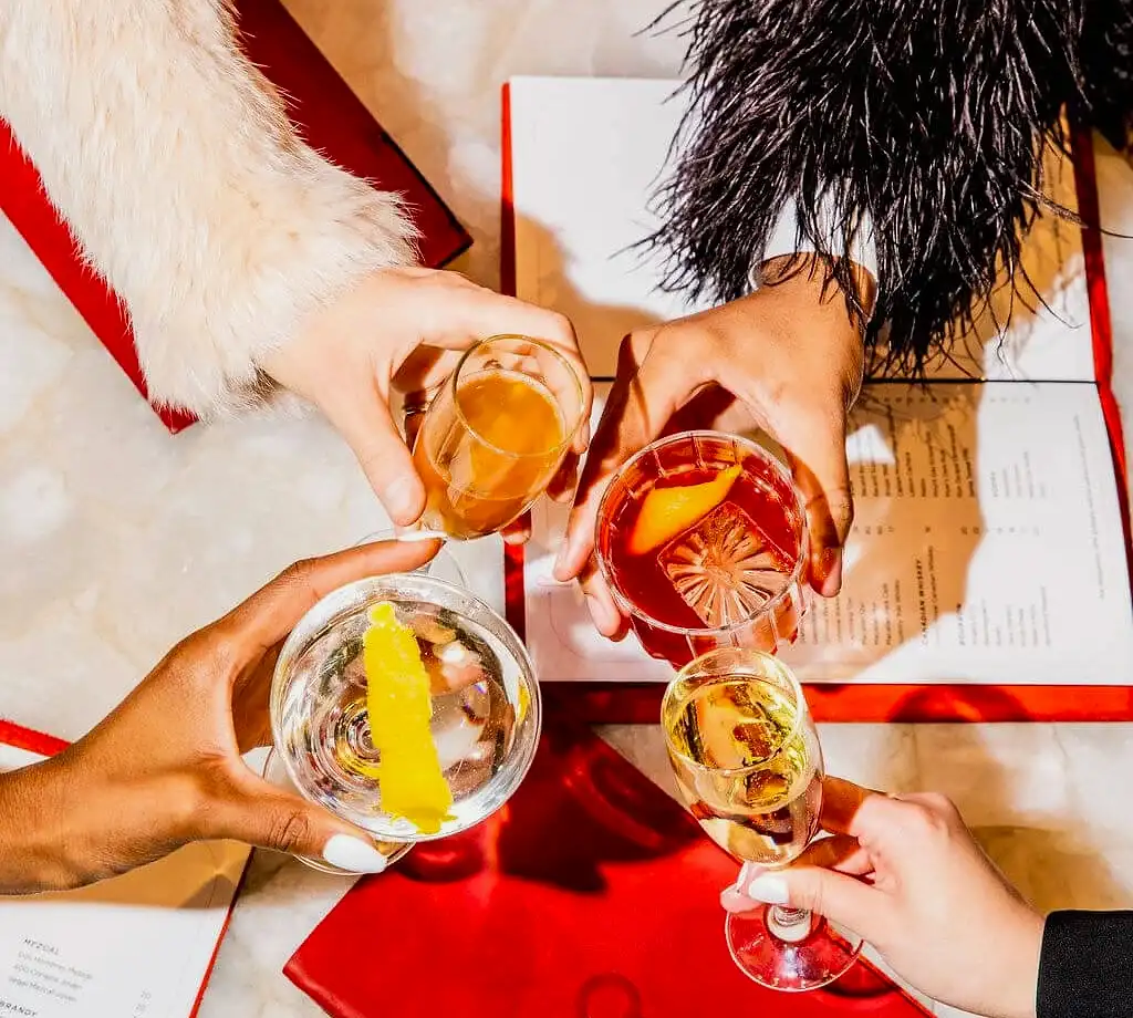 Four friends wearing formal attire clinking glasses.